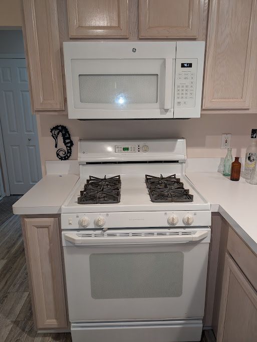 kitchen featuring light countertops, white appliances, and wood finished floors