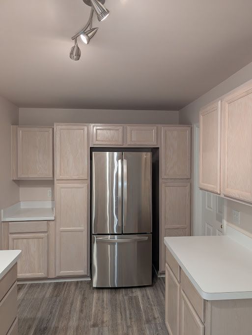 kitchen featuring light countertops, light brown cabinetry, dark wood-style flooring, and freestanding refrigerator