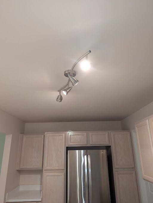 interior details with freestanding refrigerator, light countertops, and light brown cabinetry