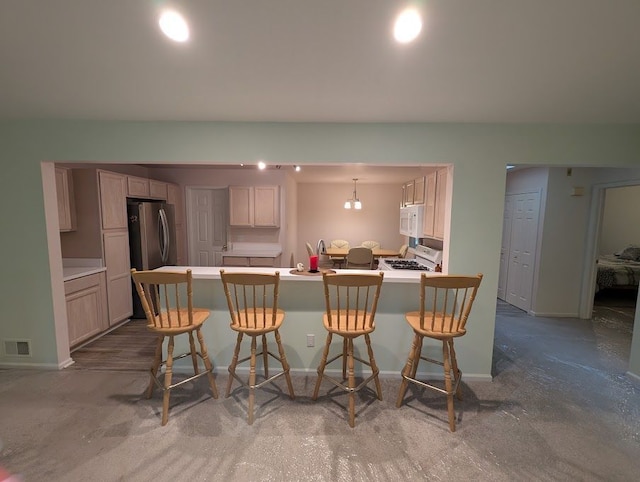 kitchen with white appliances, baseboards, visible vents, a peninsula, and a kitchen bar