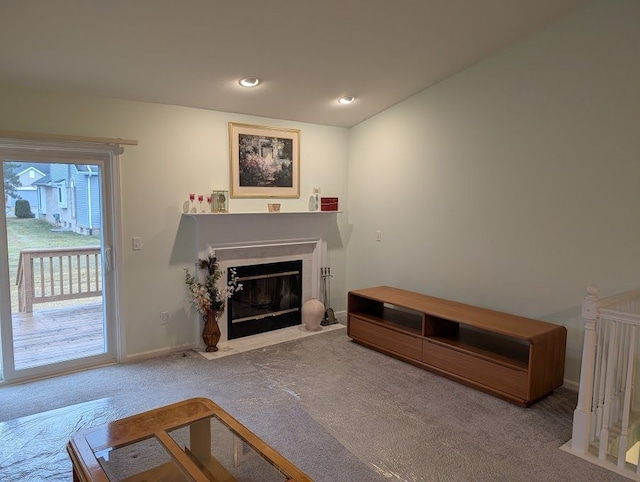 living area featuring recessed lighting, carpet, a fireplace with flush hearth, and baseboards