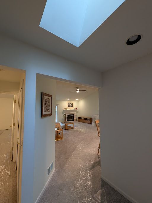 corridor featuring concrete flooring, a skylight, visible vents, and baseboards