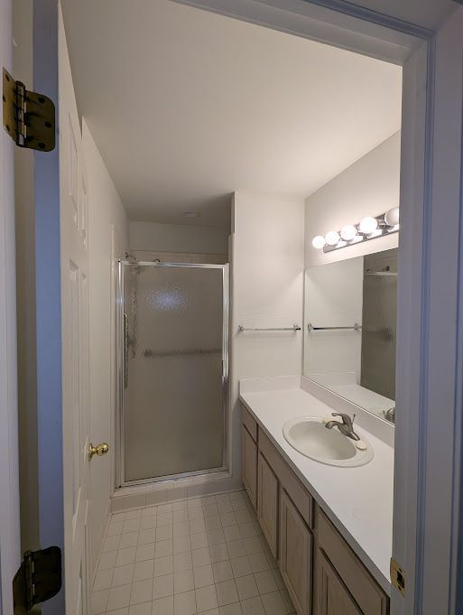 full bathroom with a stall shower, tile patterned flooring, and vanity