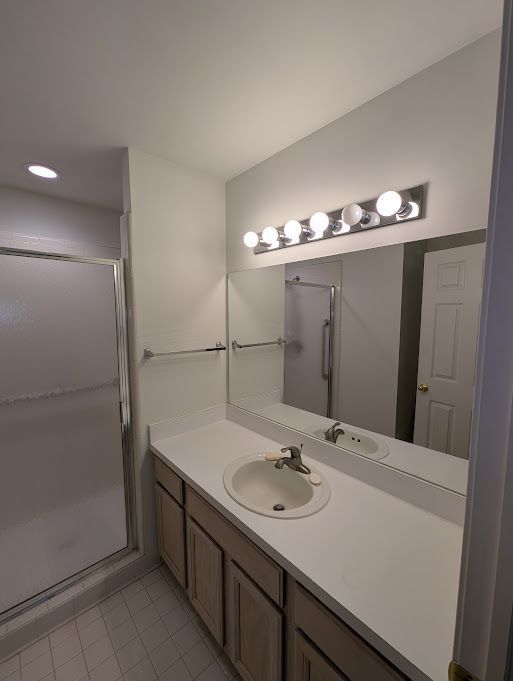 bathroom featuring tile patterned flooring, a shower stall, and vanity