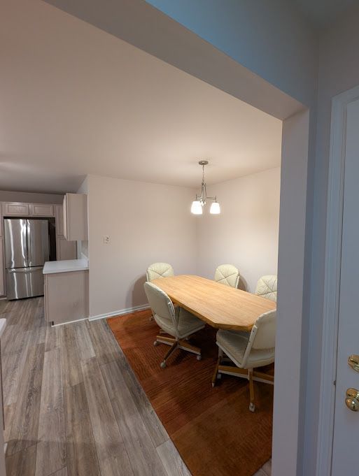 dining room with light wood-type flooring, a notable chandelier, and baseboards