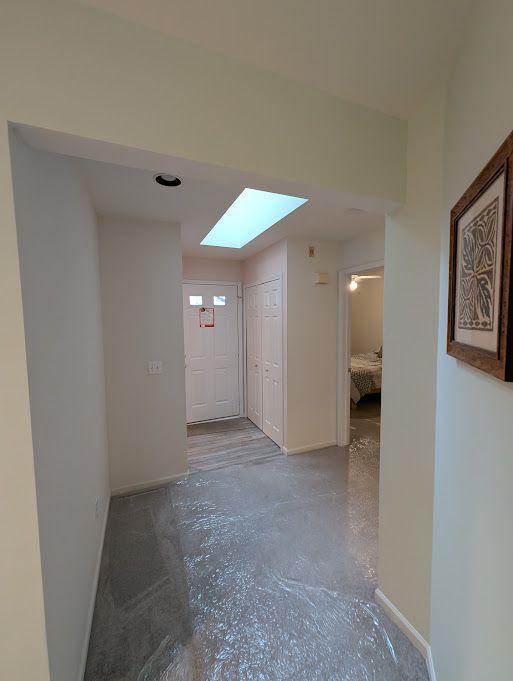 hall featuring a skylight, concrete floors, and baseboards