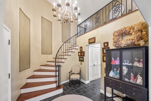 stairway with a high ceiling, baseboards, and an inviting chandelier