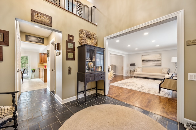 foyer entrance with stone tile floors, a high ceiling, baseboards, and recessed lighting