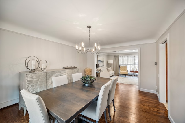 dining space featuring baseboards, a chandelier, and wood finished floors