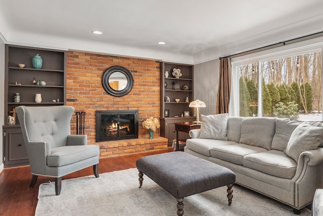 living room featuring recessed lighting, a fireplace, wood finished floors, and built in features