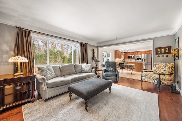 living room with an inviting chandelier, wood finished floors, and crown molding