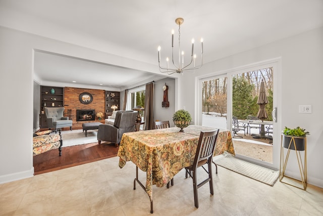 dining area with built in shelves, a fireplace, an inviting chandelier, and baseboards