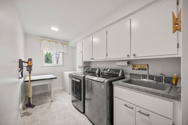 clothes washing area featuring washer and clothes dryer, a sink, cabinet space, and baseboards