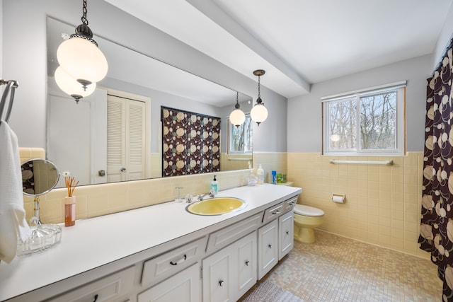 full bathroom with toilet, wainscoting, vanity, and a healthy amount of sunlight