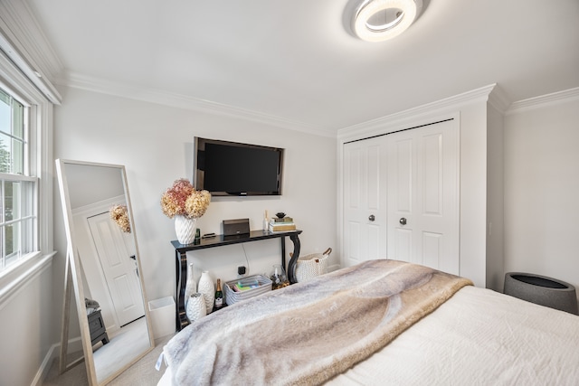 bedroom featuring baseboards, ornamental molding, a closet, and light colored carpet