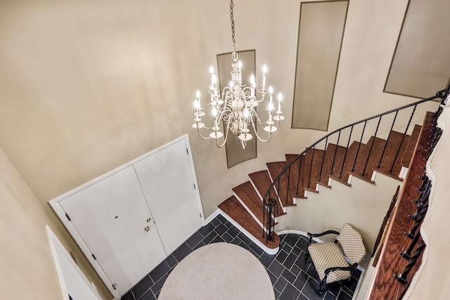 entryway with an inviting chandelier, tile patterned flooring, a high ceiling, and stairs