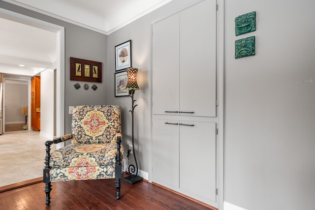 sitting room with baseboards, wood finished floors, and crown molding