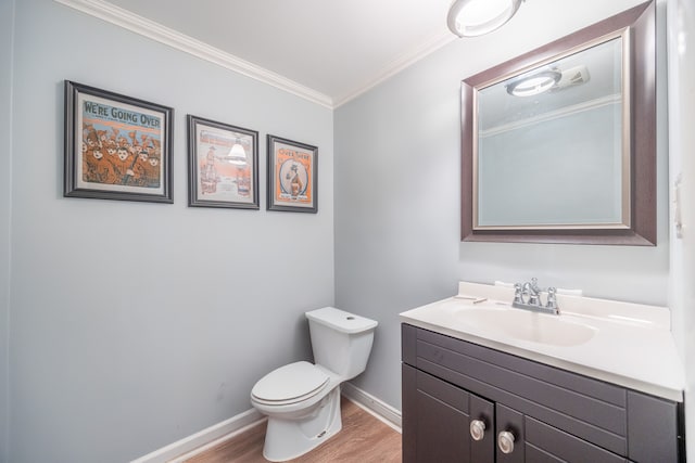 bathroom with crown molding, toilet, vanity, wood finished floors, and baseboards