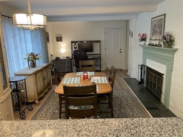 dining space featuring wood finished floors, a notable chandelier, and a glass covered fireplace