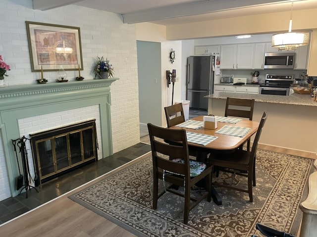 dining area featuring beamed ceiling, a fireplace, and dark wood finished floors