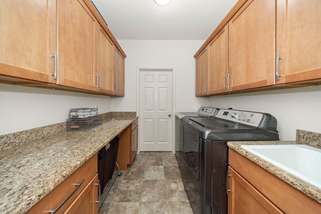 washroom with a sink, cabinet space, and washer and dryer