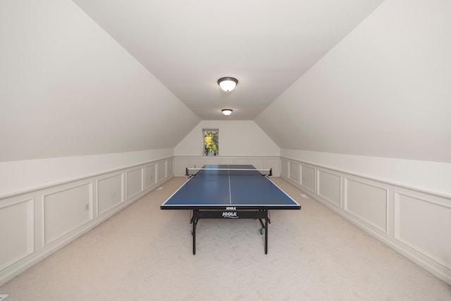 rec room featuring light carpet, a decorative wall, and lofted ceiling