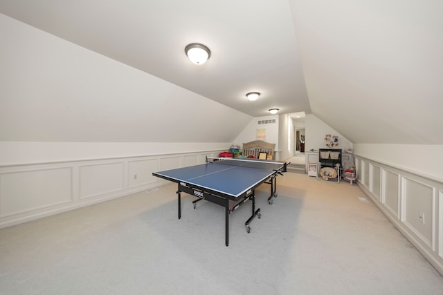 playroom featuring visible vents, light carpet, vaulted ceiling, and a decorative wall