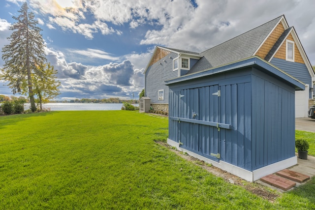 view of yard featuring a water view, an outdoor structure, and a storage shed