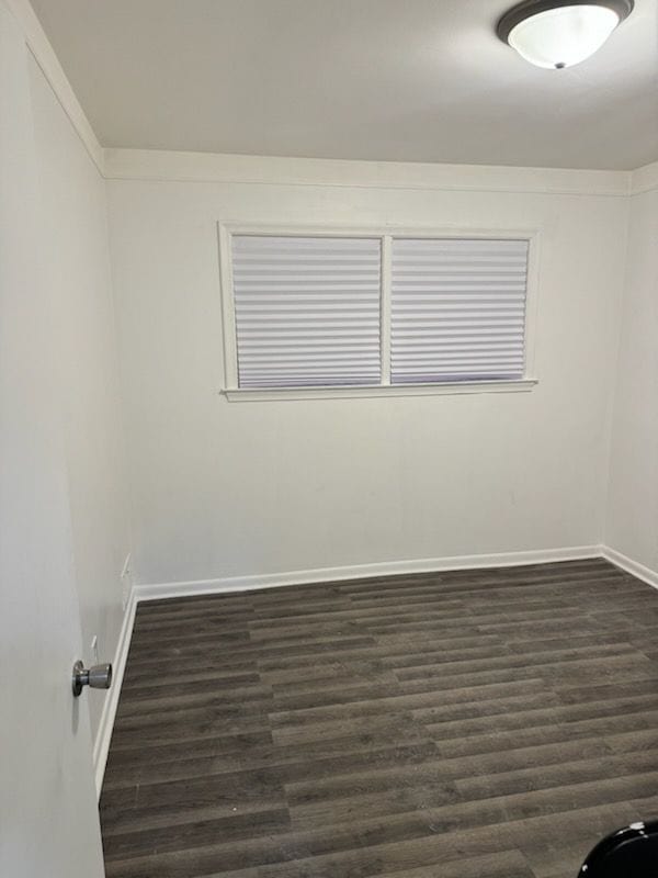 unfurnished room featuring dark wood-type flooring and baseboards