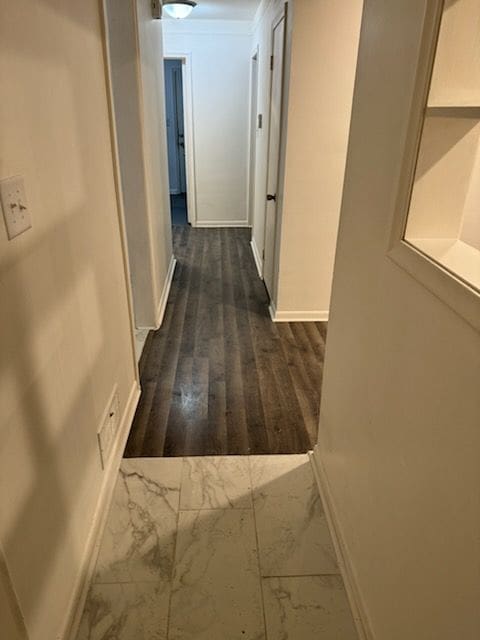 hallway with marble finish floor and baseboards