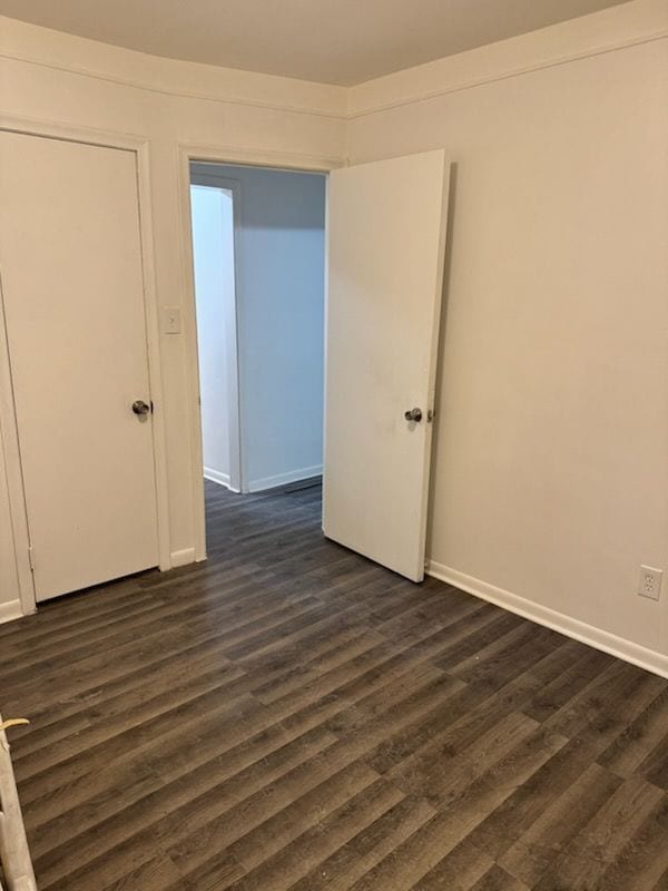 spare room featuring baseboards and dark wood finished floors