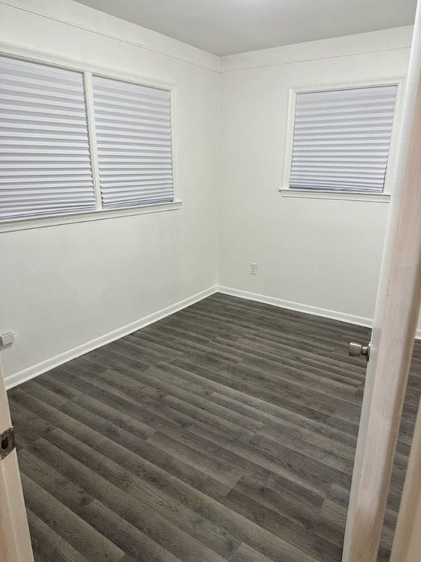 empty room with dark wood-style flooring and baseboards