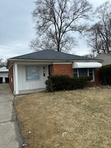 view of front of house featuring a front lawn, an outdoor structure, and brick siding