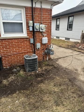 exterior details with brick siding, central AC, and electric meter