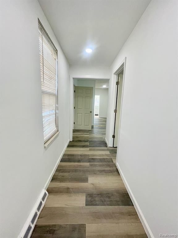 corridor with visible vents, baseboards, and wood finished floors