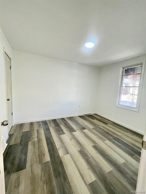 spare room with dark wood-type flooring and baseboards