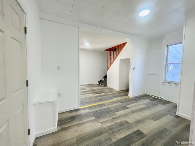 spare room with baseboards, stairway, arched walkways, and wood finished floors