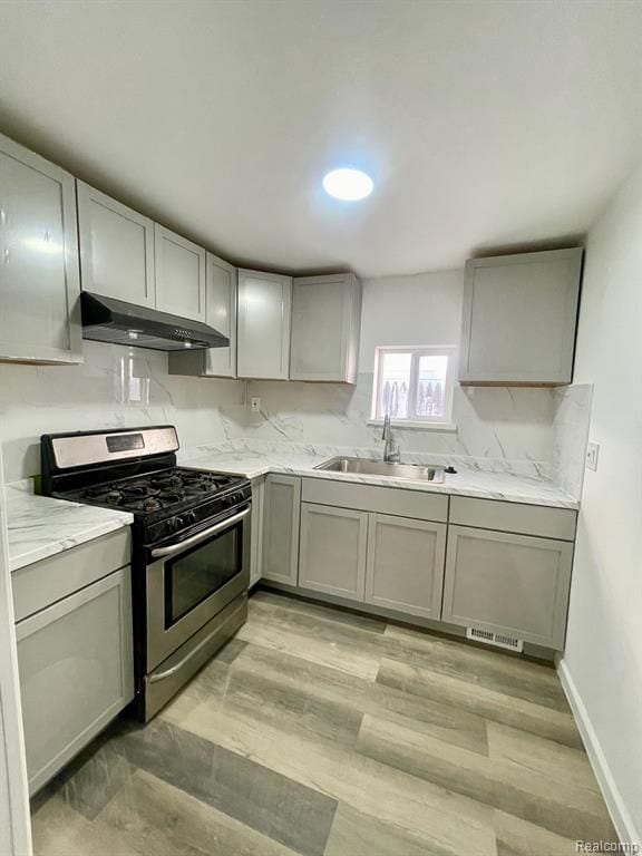 kitchen with under cabinet range hood, a sink, visible vents, gray cabinets, and stainless steel range with gas stovetop