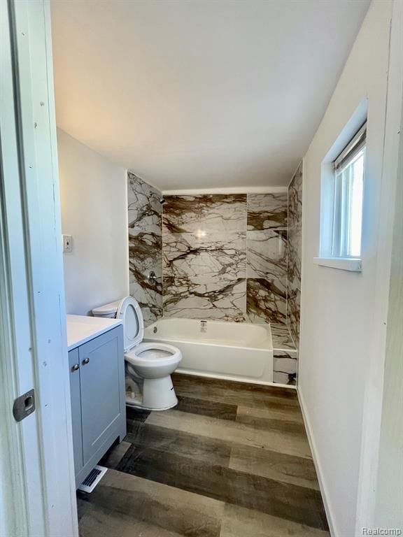 bathroom featuring visible vents, toilet, vanity, wood finished floors, and shower / bathtub combination