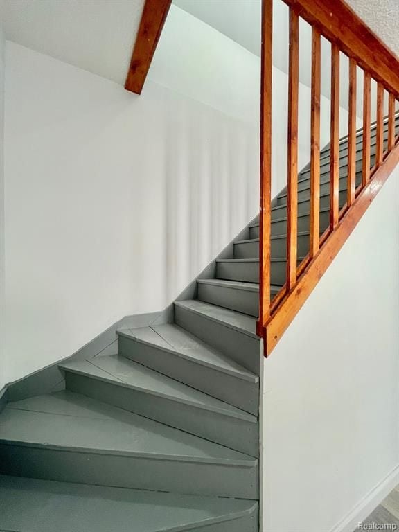 stairway featuring beamed ceiling