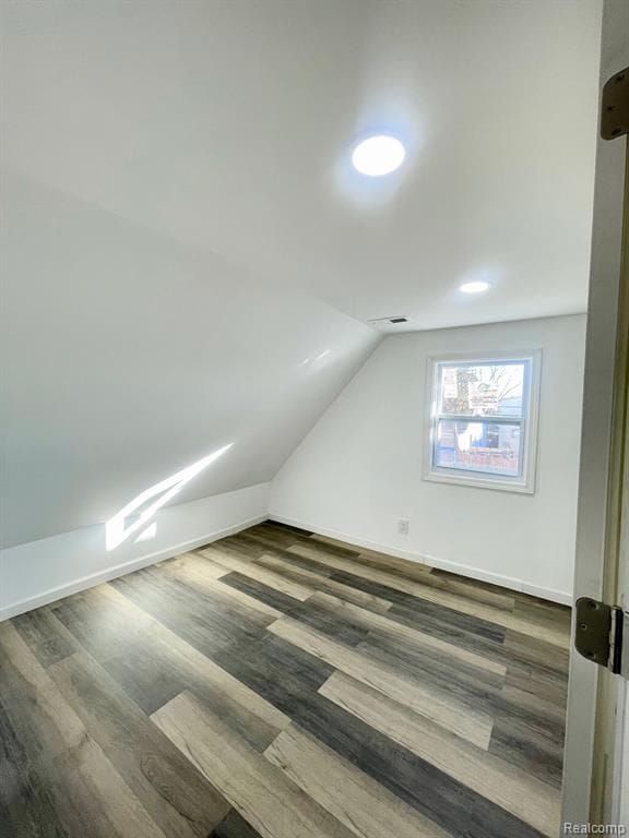 additional living space featuring lofted ceiling, visible vents, baseboards, and wood finished floors