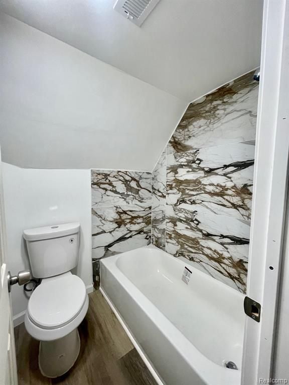 full bath featuring a washtub, visible vents, toilet, vaulted ceiling, and wood finished floors