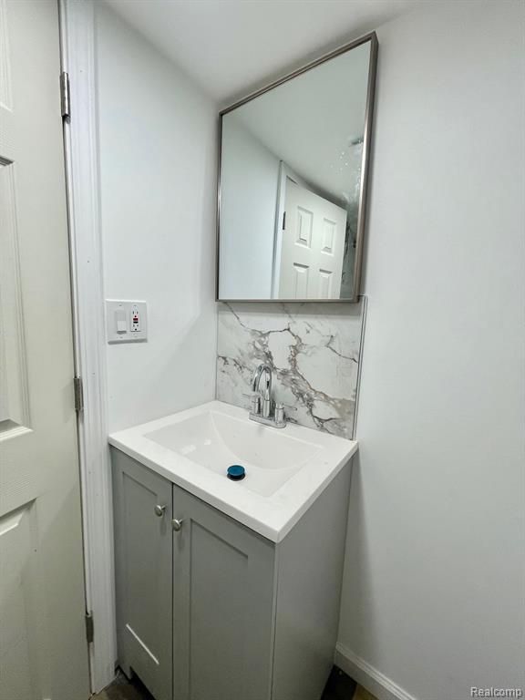 bathroom with baseboards, backsplash, and vanity