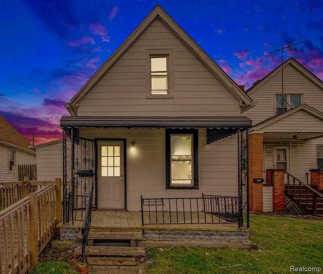 view of front of property featuring a porch, fence, and a front lawn