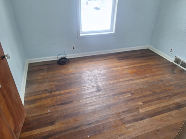 spare room with dark wood-style floors, baseboards, and visible vents