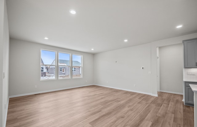 unfurnished living room with light wood-style floors, recessed lighting, and baseboards