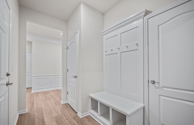 mudroom with wainscoting, a decorative wall, light wood-style flooring, and baseboards