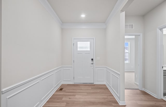 entrance foyer with visible vents, crown molding, a decorative wall, and light wood finished floors