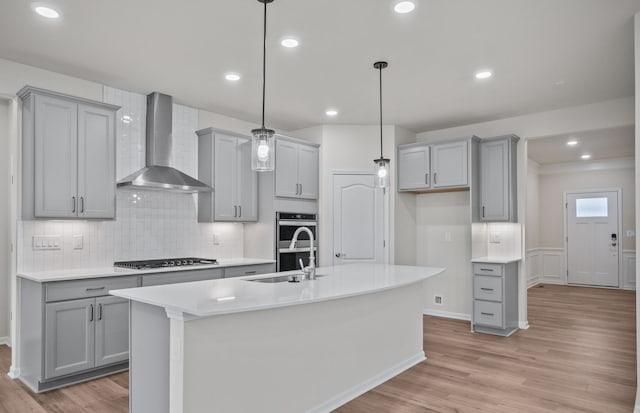 kitchen with light wood finished floors, wall chimney exhaust hood, and gray cabinets