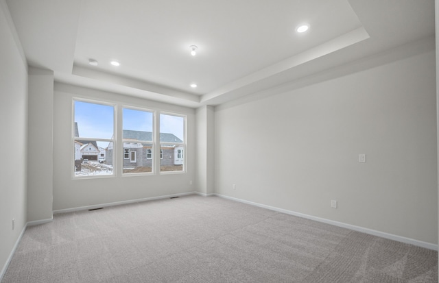 unfurnished room featuring recessed lighting, a raised ceiling, light carpet, and baseboards